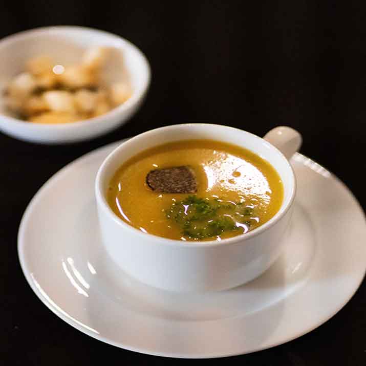 Photo of a soup entree including croutons and a glass of wine