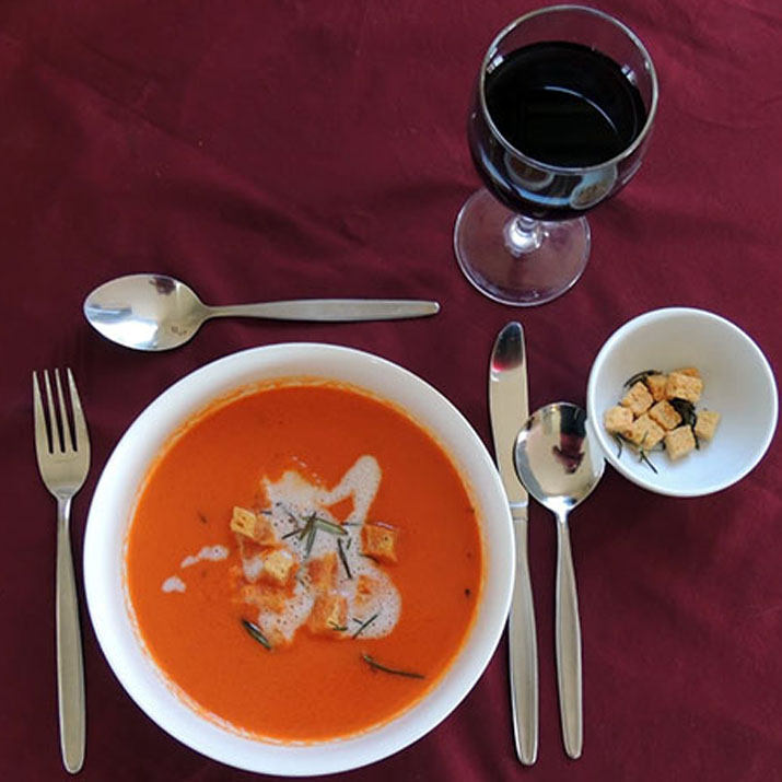 Photo of a soup entree including croutons and a glass of wine